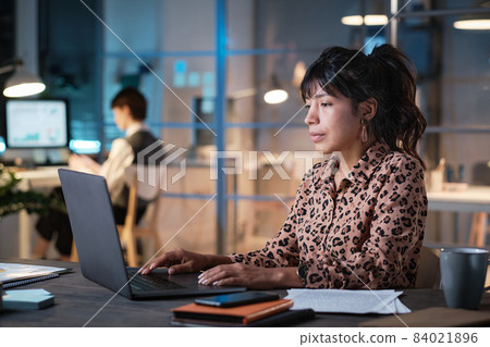 Serious businesswoman concentrating on her online work, she sitting at the table and typing on laptop while working late at office 84021896