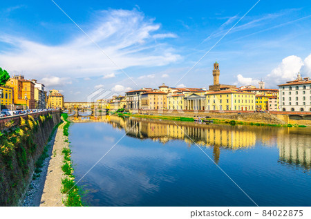 Ponte Vecchio bridge with colourful buildings houses over Arno River blue reflecting water 84022875