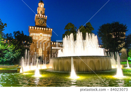 Old medieval Sforza Castle Castello Sforzesco facade, walls and tower La torre del Filarete with lights, trees 84023073