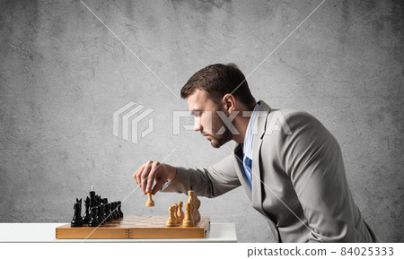 Businessman moving chess figure in chessboard 84025333