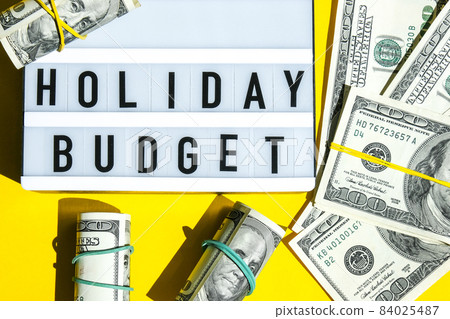 Lightbox board with word HOLIDAY BUDGET on yellow background around dollar banknotes. Money, Business, finance, investment, saving Lightbox board with word HOLIDAY BUDGET on yellow background around dollar banknotes. Money, Business, finance, investment, saving 84025487