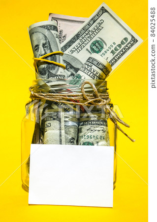 Glass jars filled with Dollar bills, savings inside glass jar, money isolated on yellow background, copy space for text. Paper note. Business budget of wealth Glass jars filled with Dollar bills, savings inside glass jar, money isolated on yellow background, copy space for text. Paper note. Business budget of wealth 84025488