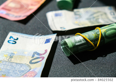 Close up of Euro money roll. Euro banknote set cash money - EU currency. Rolled with rubber euro notes. Banknotes stacked on each other in different positions Close up of Euro money roll. Euro banknote set cash money - EU currency. Rolled with rubber euro notes. Banknotes stacked on each other in different positions 84025502