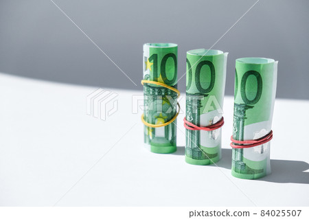 Close up of Euro money roll. Euro banknote set cash money - EU currency. Rolled with rubber euro notes. Banknotes stacked on each other in different positions 84025507
