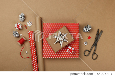 Packing Christmas gifts with red paper 84025805