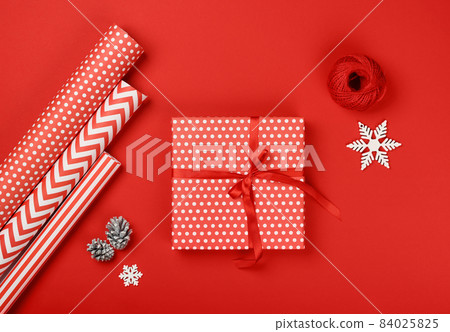 Packing Christmas gifts with red and white paper 84025825