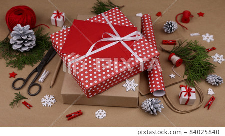 Packing Christmas gifts with red paper 84025840