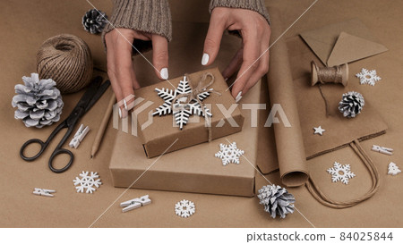 Woman packing Christmas gifts in brown paper 84025844