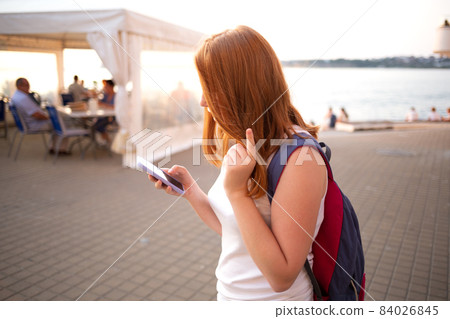red-haired teen girl writes a message on the phone red-haired teen girl writes a message on the phone 84026845