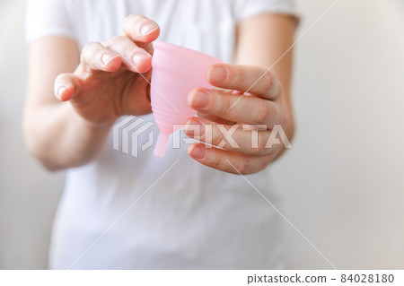 Woman hand holding pink menstrual cup Isolated on white background. Woman modern alternative eco gynecological hygiene in menstruation period. Container for blood in girl hand. 84028180