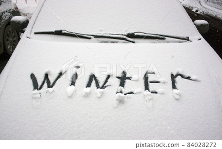 The car is covered with white fluffy snow. On the hood it says winter The car is covered with white fluffy snow. On the hood it says winter 84028272