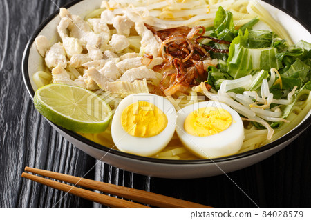 Soto Ayam is a chicken noodle soup popular in Malaysia and Indonesia close up in the plate. Horizontal Soto Ayam is a chicken noodle soup popular in Malaysia and Indonesia close up in the plate. Horizontal 84028579