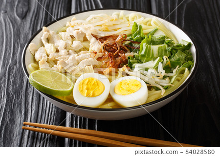 Indonesian 'Soto Ayam' Chicken Noodle Soup in a spicy broth close up in the plate. Horizontal 84028580