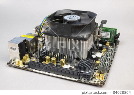 Computer motherboard with memory sticks and a cooler on a gray background. PC hardware Computer motherboard with memory sticks and a cooler on a gray background. PC hardware 84028804