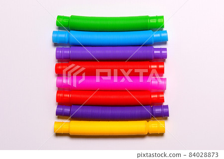 Row of bright new straight pop tubes on white paper background Row of bright new straight pop tubes on white paper background 84028873