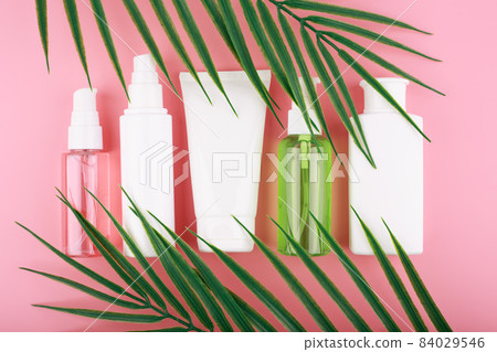 Flat lay with cosmetic set on pink background with palm leaves 84029546