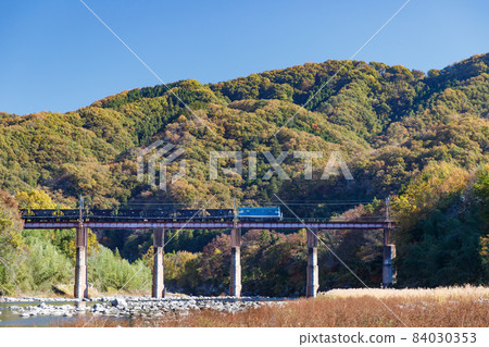 Nagatoro Arakawa Bridge, a freight train that makes noise against the backdrop of the blue sky and autumn mountains 84030353