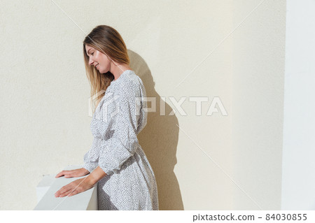 a beautiful woman in a white dress standing on the balcony looking outside a beautiful woman in a white dress standing on the balcony looking outside 84030855