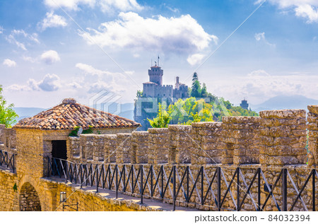 Stone brick fortress wall with merlons of Prima Torre Guaita first tower and Seconda Torre La Cesta second tower Stone brick fortress wall with merlons of Prima Torre Guaita first tower and Seconda Torre La Cesta second tower 84032394
