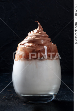 Dalgona cold coffee in a glass on a black background. Trendy Korean milk shake Dalgona cold coffee in a glass on a black background. Trendy Korean milk shake 84032922