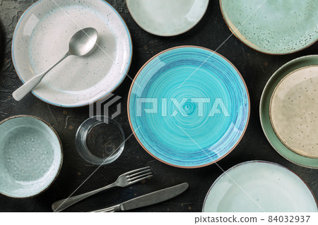 Modern tableware set with cutlery and a vibrant blue plate, top shot 84032937