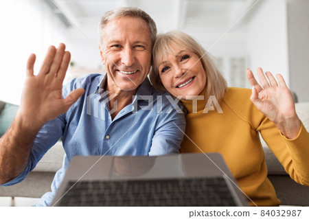 Senior Spouses Video Calling Using Laptop Waving Hands At Home Senior Spouses Video Calling Using Laptop Waving Hands At Home 84032987