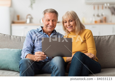 Happy Mature Couple Using Laptop Browsing Internet Together At Home 84033113