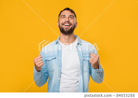 Satisfied happy mature caucasian man rejoices to success and looks up, isolated on yellow background Satisfied happy mature caucasian man rejoices to success and looks up, isolated on yellow background 84033288