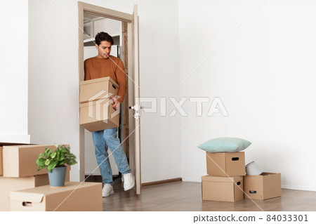Guy holding cardboard boxes, walking in new house 84033301