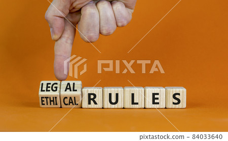 Ethical or legal rules symbol. Businessman turns wooden cubes and changes words 'ethical rules' to 'legal rules' on a beautiful orange background. Business, ethical or legal rules concept. Copy space. 84033640
