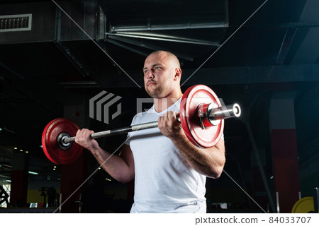 Male athlete lifts the barbell 84033707