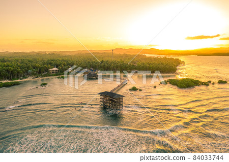 Aerial shot a sunset on wooden building in the middle of the waters of General Luna, Siargao Island 84033744