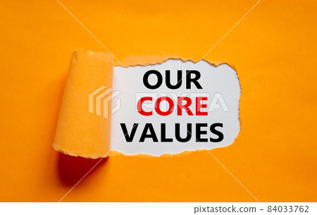 Our core values symbol. Words 'Our core values' appearing behind torn orange paper. Beautiful orange background. Business, our core values concept, copy space. 84033762
