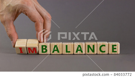 Balance or imbalance symbol. Businessman turns cubes and changes the word imbalance to balance. Beautiful grey background, copy space. Business, balance or imbalance concept. 84033772