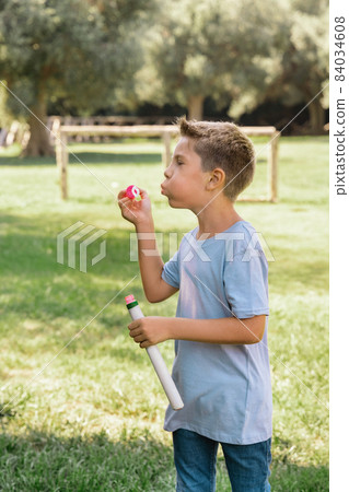 Kid boy blowing soap bubbles in a park in a sunny day 84034608
