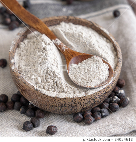 Bowl of black chickpea flour and beans with a wooden spoon closeup Bowl of black chickpea flour and beans with a wooden spoon closeup 84034618