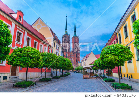 Street with cobblestone road with green trees, colorful buildings, summer cafe Street with cobblestone road with green trees, colorful buildings, summer cafe 84035170