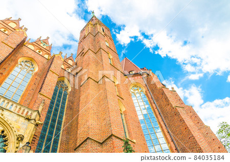 View from below of brick tower wall with spire of Collegiate Church of Holy Cross and St. Bartholomew catholic church View from below of brick tower wall with spire of Collegiate Church of Holy Cross and St. Bartholomew catholic church 84035184