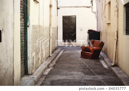 Brown leather armchair abandoned on the narrow old town street Brown leather armchair abandoned on the narrow old town street 84035777