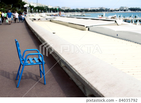 Blue chair on paved road seashore view on sea and sky with people 84035792