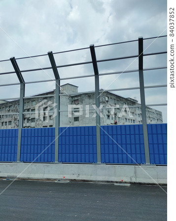 SELANGOR, MALAYSIA - JULY 5, 2020: Noise barriers are installed along the vehicle lane bordering the residence to prevent noise pollution to the surrounding locals. 84037852