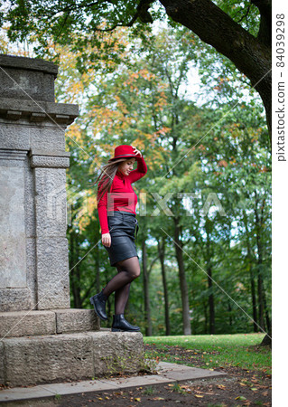 Woman in bright red near monument in park Woman in bright red near monument in park 84039298