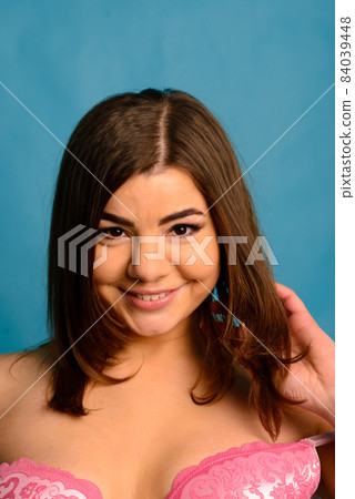Beautiful emotional plus-size female model in pink and black bodysuit posing on background in studio 84039448
