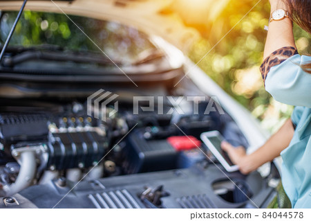 Business women have car problems on the side of the road.The light is golden at sunset. Young women calling car mechanic. Concept of quality inspection of cars Engine maintenance all the time. Business women have car problems on the side of the road.The light is golden at sunset. Young women calling car mechanic. Concept of quality inspection of cars Engine maintenance all the time. 84044578