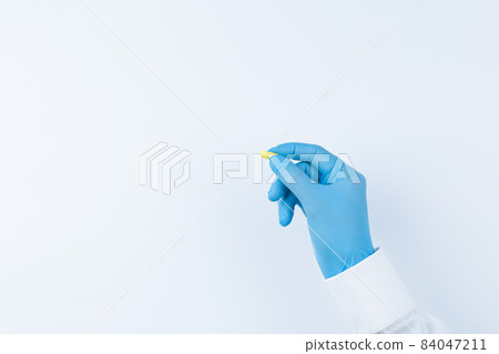 Doctor offers a yellow pill top view. 84047211