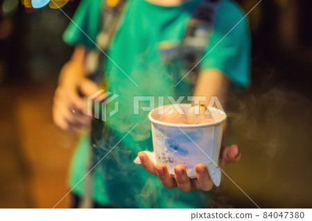 The boy is eating corn sticks spilled with liquid nitrogen 84047380