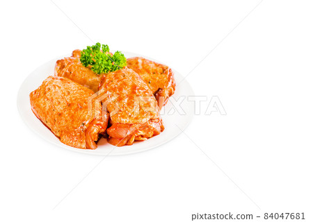 Chicken semi-cooked thighs.Raw marinated in red sauce chicken thighs on a white plate, on a white isolated background.Raw chicken marinated. Isolated object, copy space.Top of view. 84047681
