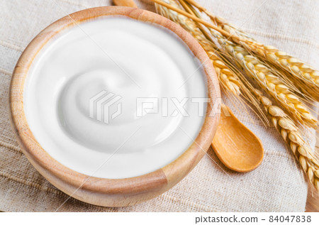 Greek yogurt in a wooden bowl and dry barley. 84047838