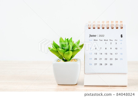 June 2022 desk calendar on wooden table. 84048024