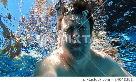 a man dives into the pool with a camera in his hands. shooting under water. a man dives into the pool with a camera in his hands. shooting under water. 84048391